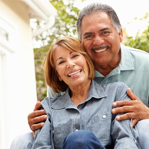 smiling older couple outside their house