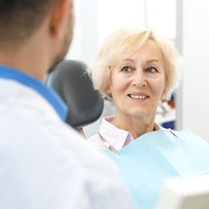 Older woman smiling at dentist while sitting in dental chair