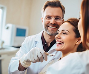 Woman in dental chair smiling next to a happy dentist
