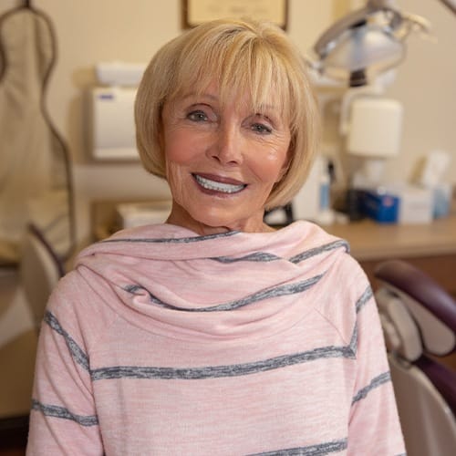 Woman in dental chair smiling after full mouth reconstruction
