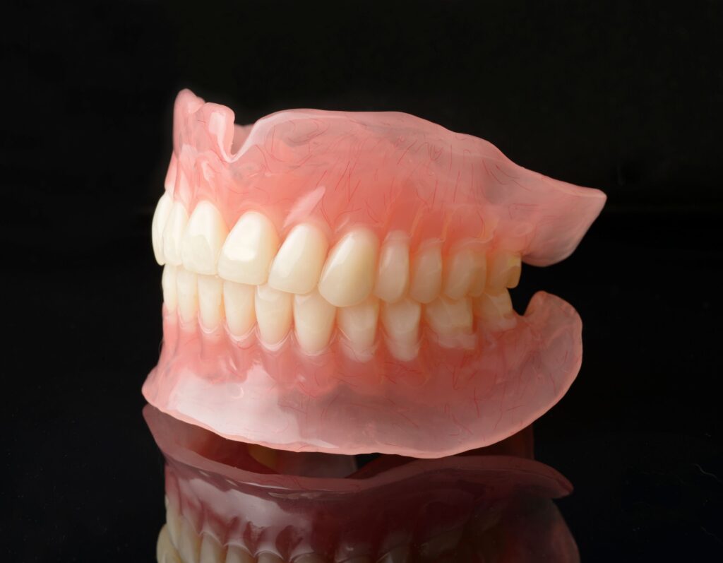 3/4 profile view of full set of dentures on reflective black surface